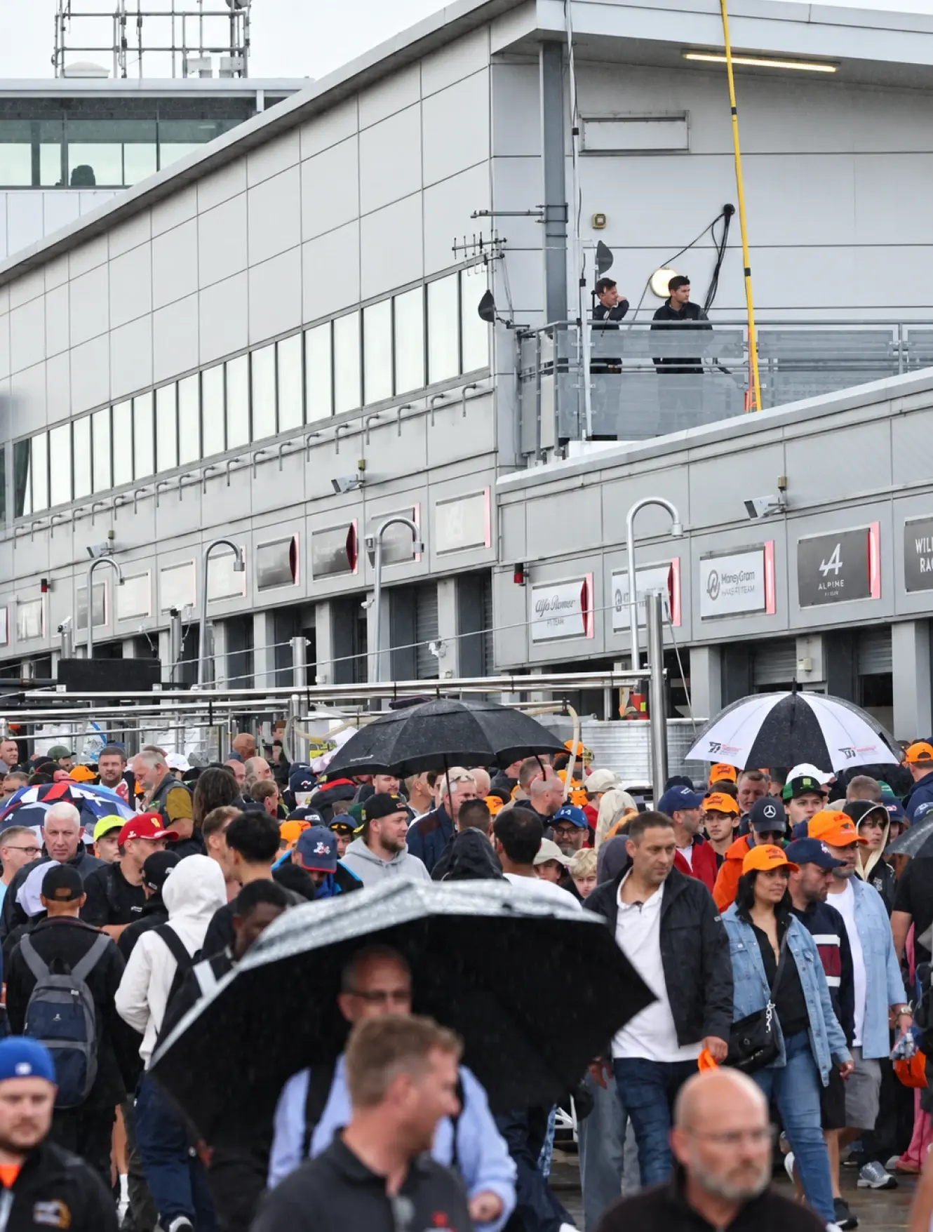 A grid girl holding an SRO board beside the number 84 Mahiki Racing McLaren Artura GT4 on the grid
