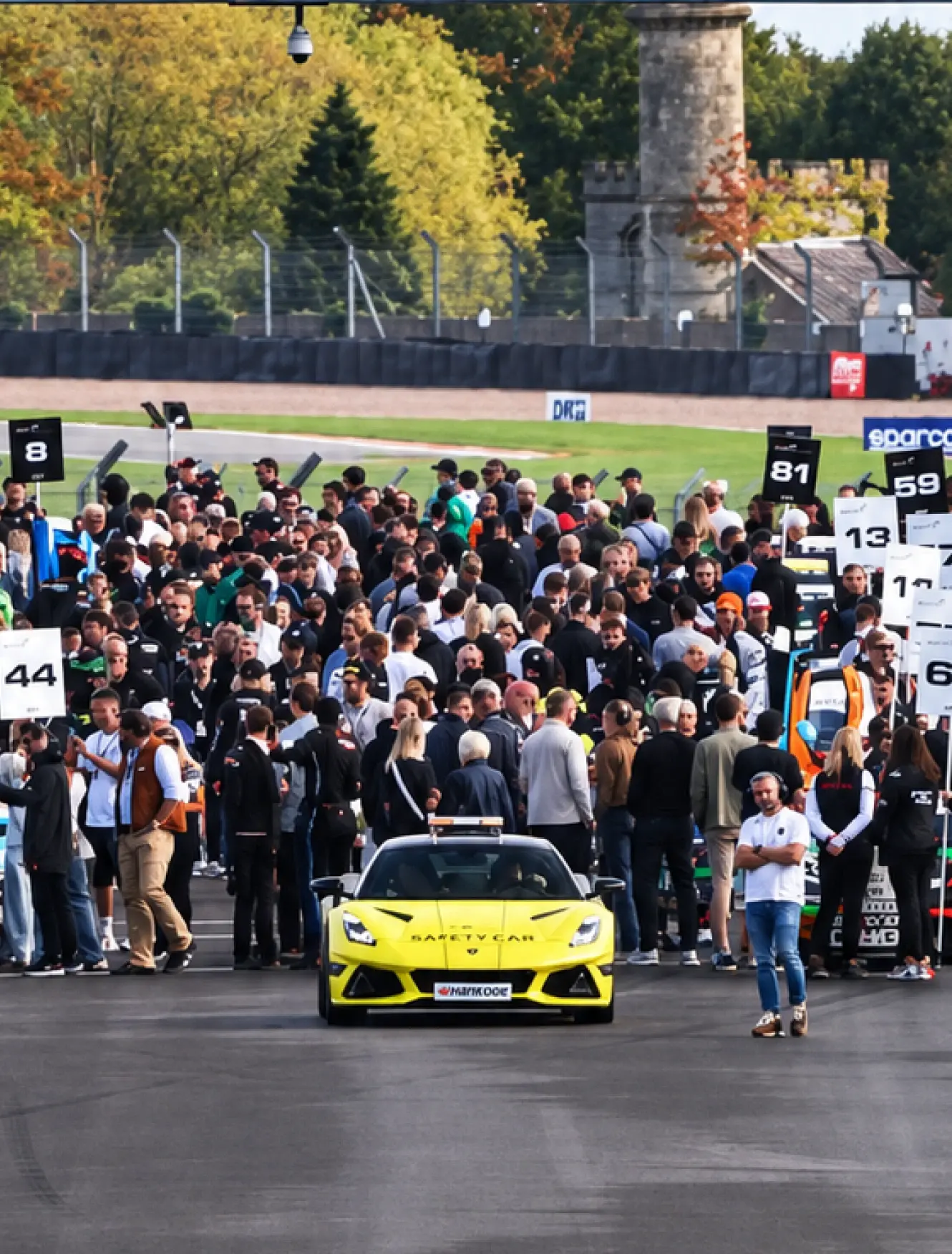 Revie Lake in Mahiki Racing overalls on the grid with the crowd behind him